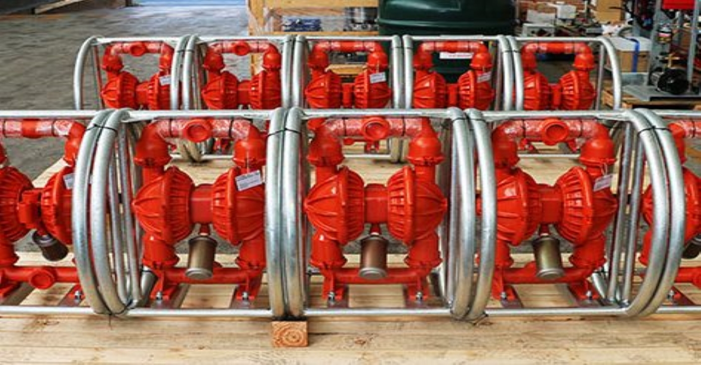 Multiple bright red Wilden Air-Operated Double Diaphragm (AODD) pumps with aluminum wetted parts, mounted in protective pipe frames and ready for abrasive slurry and chemical transfer