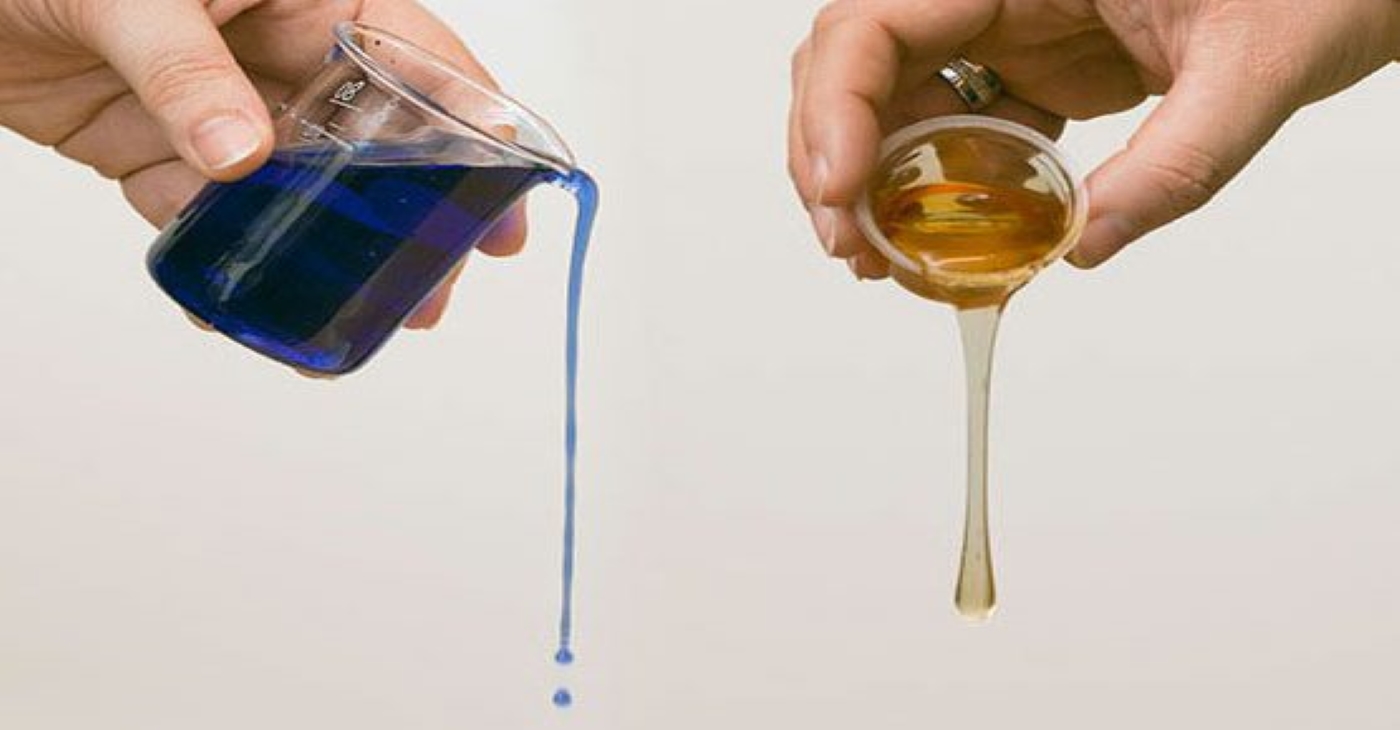 comparison of low-viscosity blue liquid and high-viscosity amber fluid being poured from laboratory containers to demonstrate differences in flow behavior and viscosity levels for industrial fluid handling applications