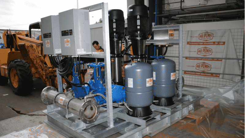 Large packaged Grundfos variable speed pressure booster system with twin vertical multistage pumps and accumulator tanks, pre-assembled on a skid for commercial HVAC or high-rise water supply