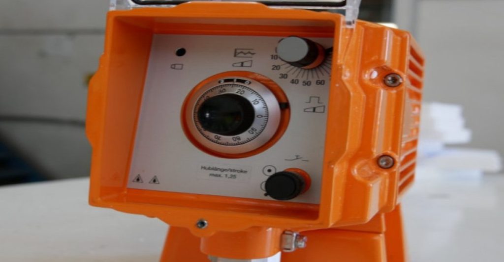 Close-up of an orange industrial metering or dosing pump control panel with a dial for setting stroke length and frequency for chemical injection or All-pumps precision fluid control