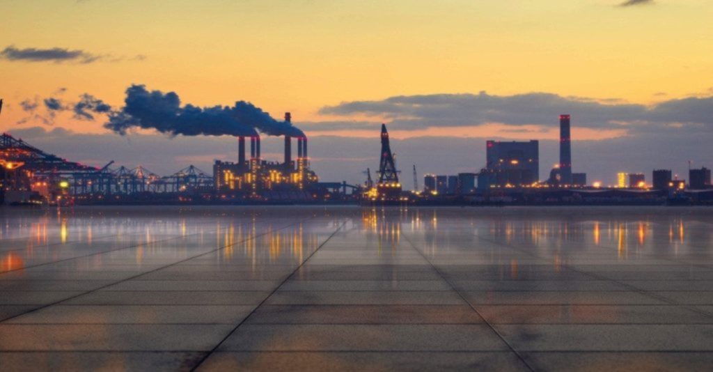 Industrial oil refinery or chemical processing plant skyline at sunset, representing the heavy-duty fluid transfer applications of Tuthill process pumps in manufacturing