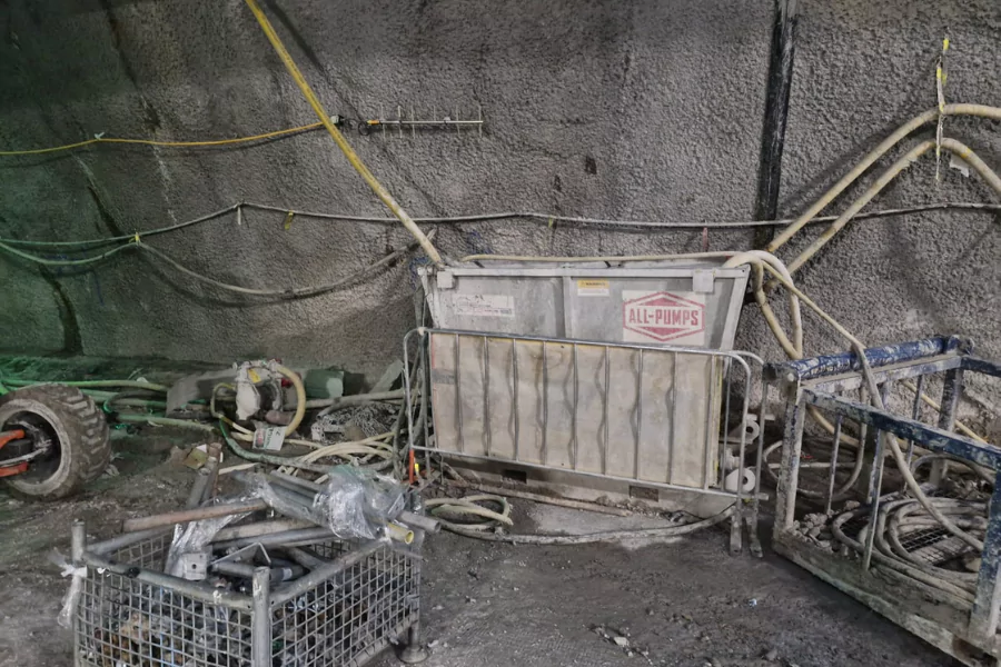 Industrial ALL-PUMPS dewatering and slurry management system (CS) used in a tunnelling project, featuring a pump and collection tank on a rugged job site with concrete-sprayed walls