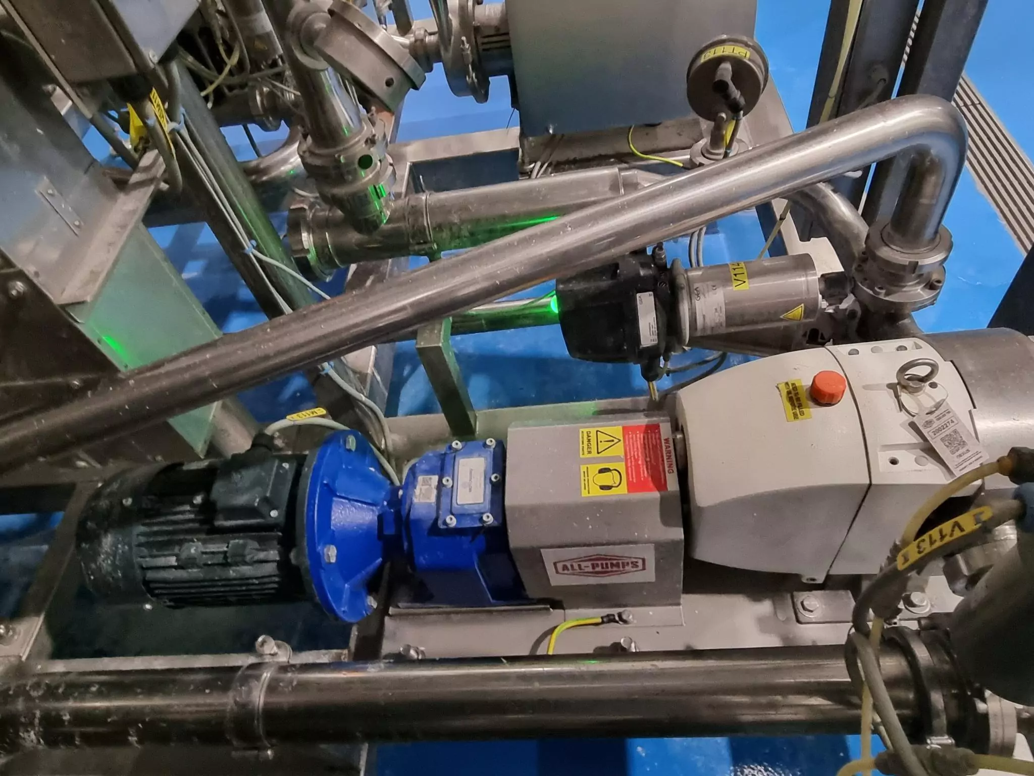 Close-up installation view of an All-Pumps supplied Jabsco lobe pump replacement unit with a blue gearbox and electric motor, used for sanitary and gentle fluid transfer in a food or pharmaceutical facility