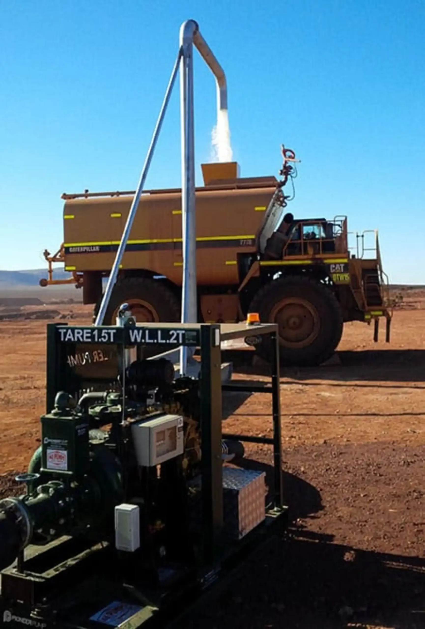 Rugged diesel transfer pumpset on a skid filling a large Caterpillar mining water truck, demonstrating on-site bulk fluid transfer and high-flow capability for dust suppression and industrial applications