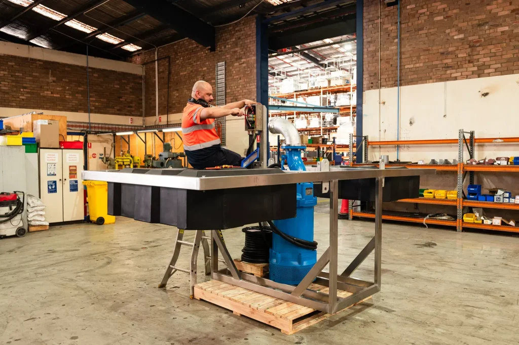Worker assembling a large pump in a workshop.