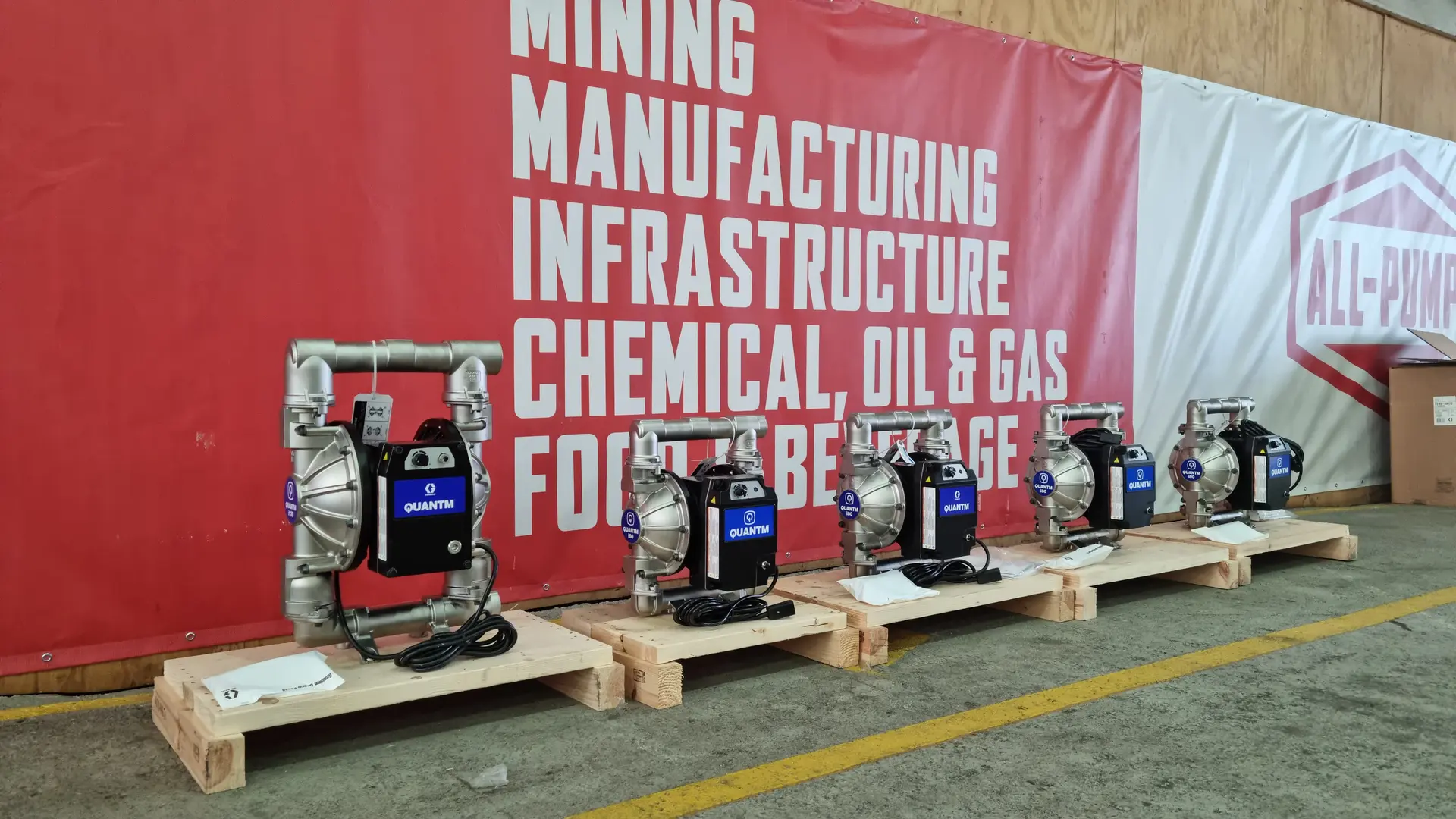Black and blue Graco QUANTM pumps against a red industry graphic