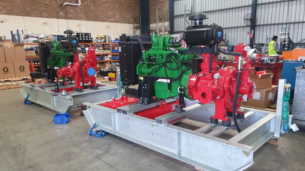 Green and red dewatering pump sets in a workshop